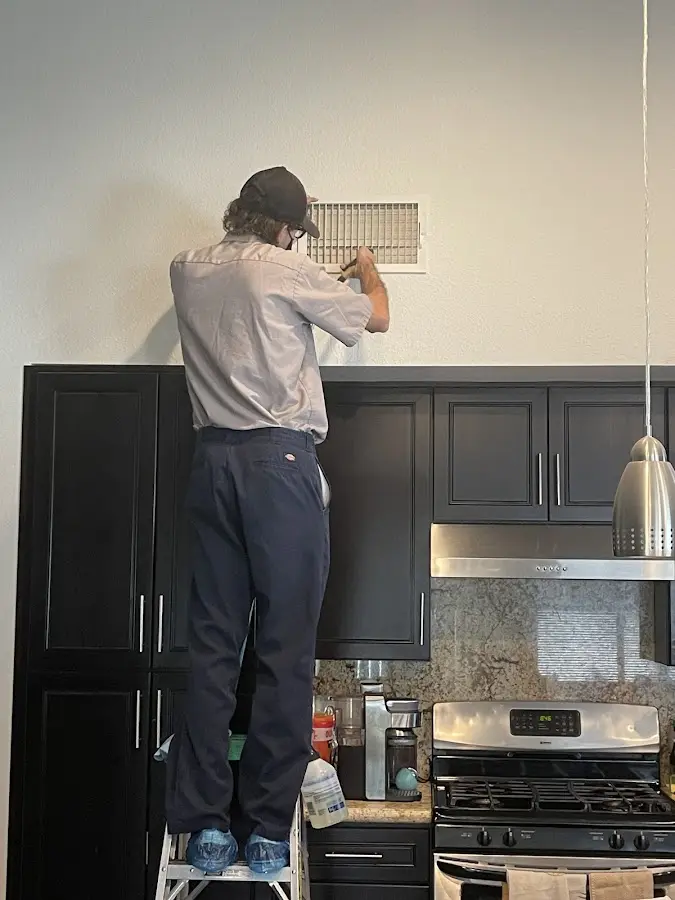 Technician inspecting an air vent during HVAC service in Victoria